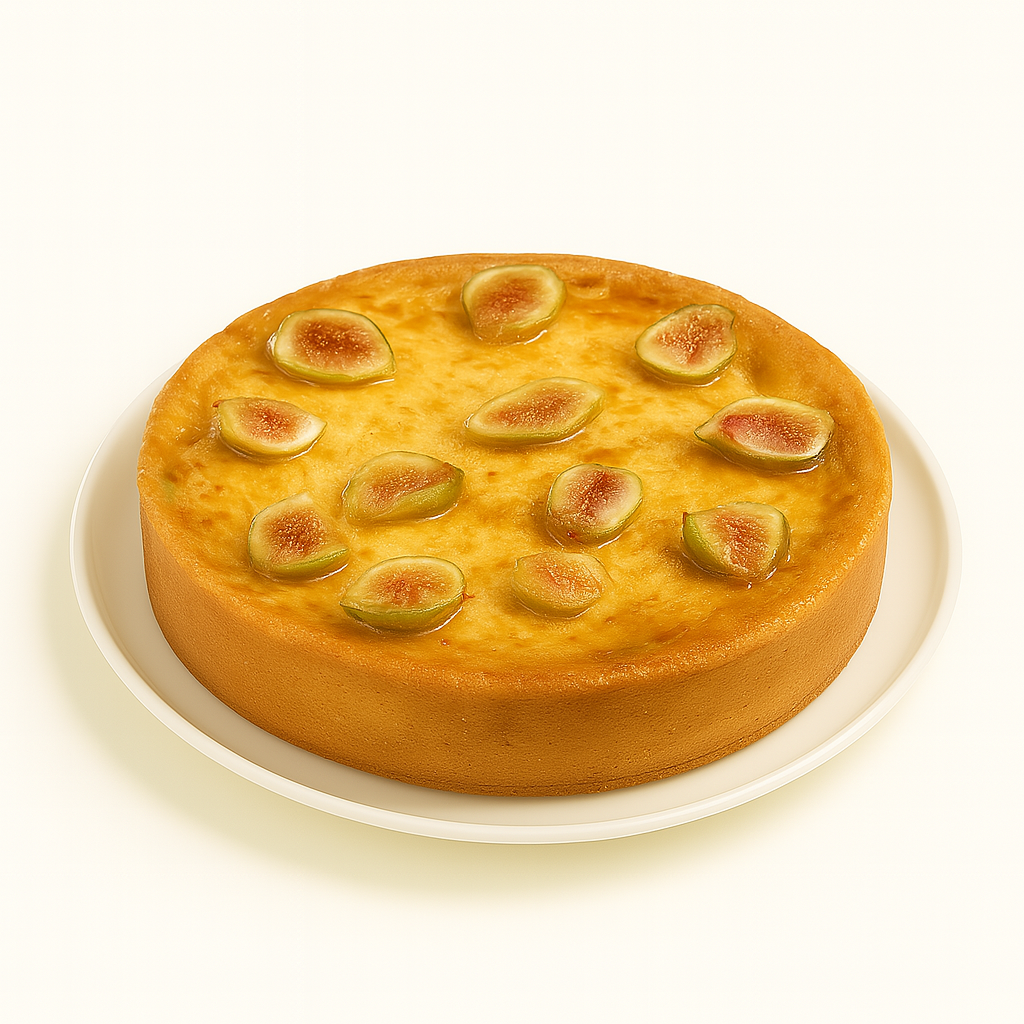 An American fig cheesecake shown from a slight side angle on a white ceramic plate. The cheesecake has a golden-brown crust and a glossy top adorned with halved green figs, placed against a clean white background.