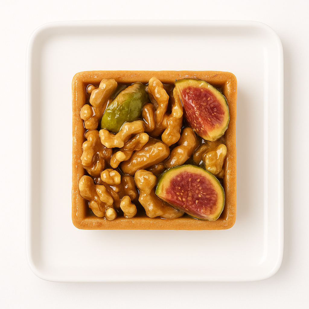 An overhead view of a square tart on a white square plate. The tart is filled with caramelized walnuts, green candied fruits, and two slices of ripe fig, showing their red-purple interiors.