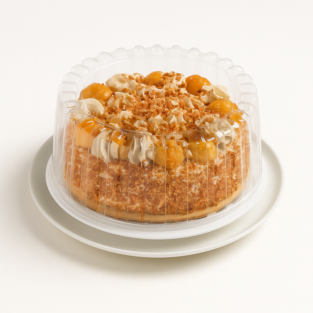 A whole hazelnut semifreddo cake in a clear plastic dome container, displayed on a white round plate against a plain white background. The cake is decorated with swirls of cream, caramelized hazelnut puffs, and sprinkled hazelnut pieces on top and around the sides.