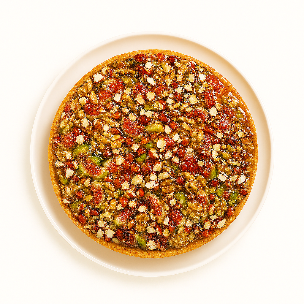 A top-down view of a nut and fruit tart displayed on a white ceramic plate, featuring a golden-brown crust and a colorful topping of chopped nuts and pieces of fruit coated in a glossy glaze, all set against a clean white background.