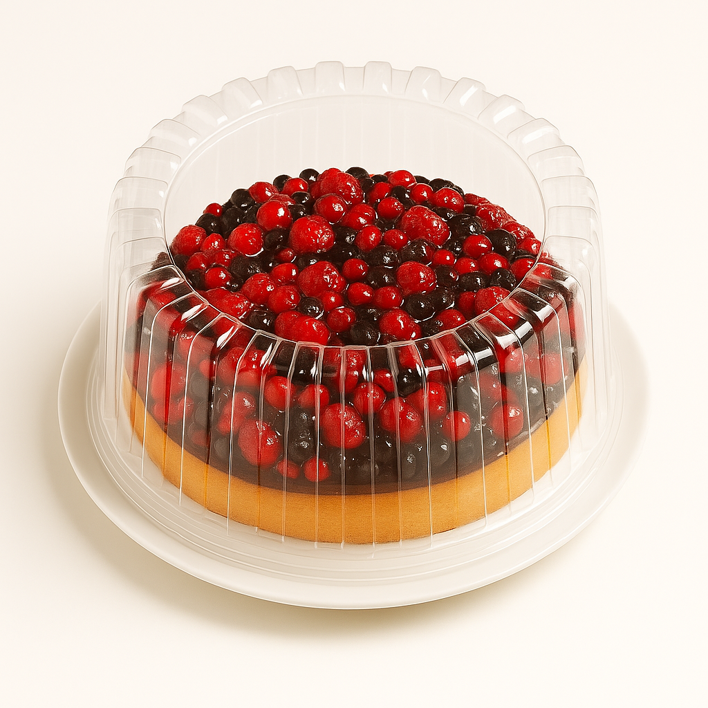 A wild berry tart enclosed in a clear plastic dome container sits on a white plate against a plain white background. The tart’s surface is covered with glossy red and dark berries, visible through the ribbed plastic lid, and the light golden crust peeks out from beneath the topping.