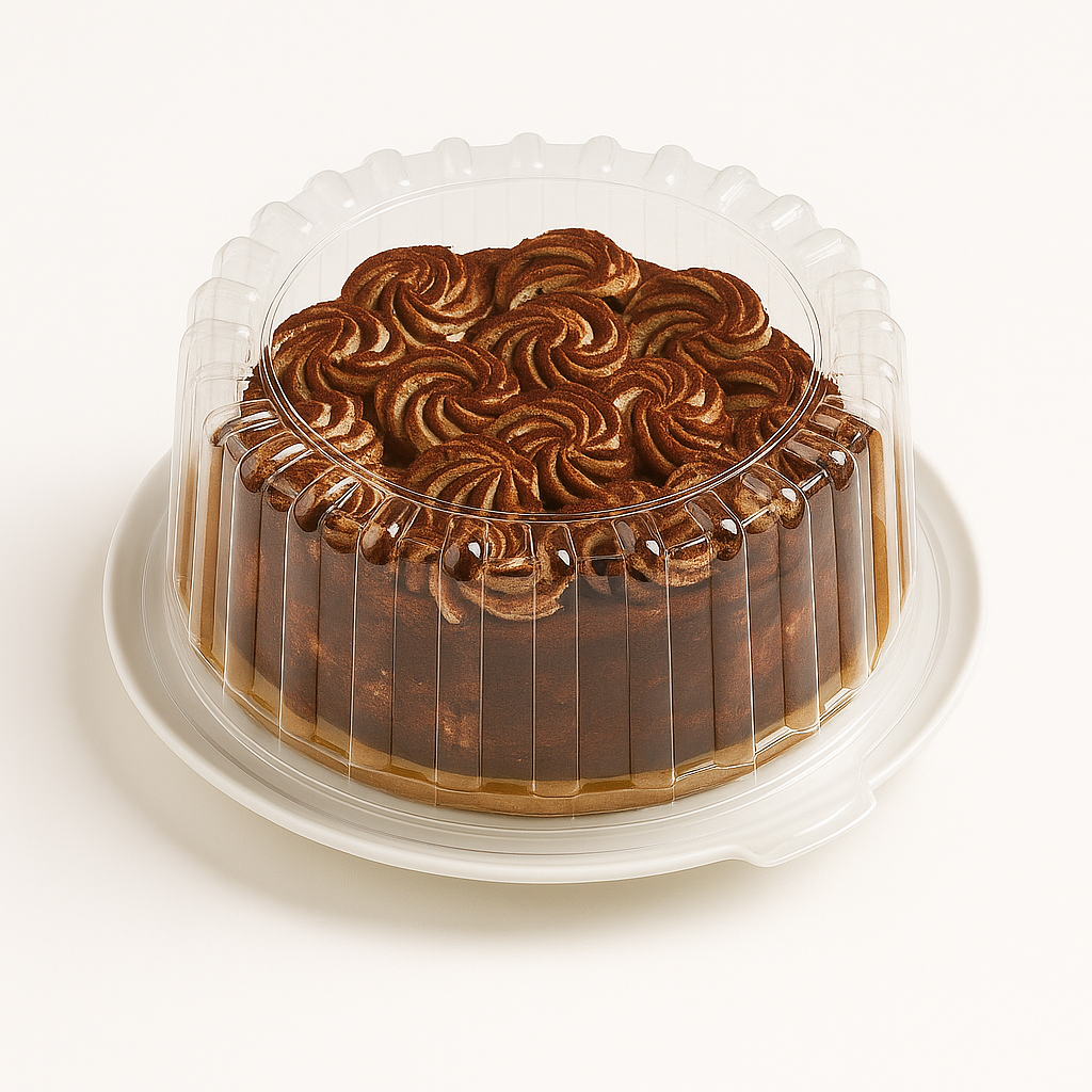 A tiramisu semifreddo cake in a clear plastic dome container placed on a white cake plate, photographed against a plain white background, showcasing its decorative cocoa-swirled top and layered sides.